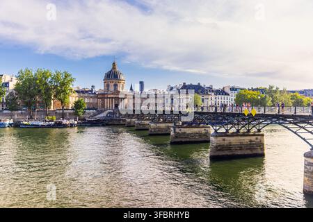 PARIS, FRANKREICH - 20. JULI 2026: Touristen überqueren die Fußgängerbrücke Pont des Arts über die Seine in Richtung Institut de France in Paris. Stockfoto