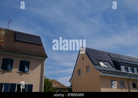 Zwei Wohnhäuser mit auf dem Dach installierten Solarpanelen unter einem klaren blauen Himmel mit leichten Wolken. Stockfoto
