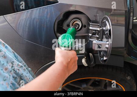 Handbetankung eines grauen Autos mit grünem Kraftstoffschlauch Stockfoto