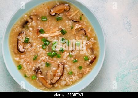 Dichte Congee-Reissuppe mit Huhn, Shiitake-Pilzen und grünen Zwiebeln, Ansicht von oben. Stockfoto