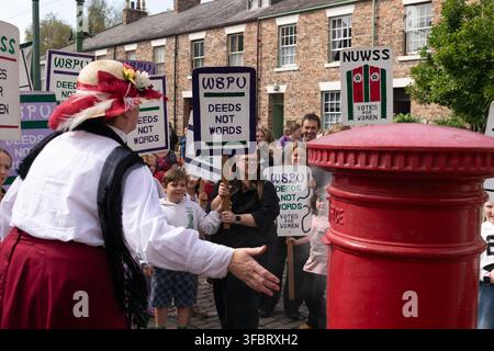Nachbildung der Suffragette Lady Rhondda, die einen Briefkasten in die Luft sprengt. Plakate in der Menge Deeds not Words, Beamish Museum, Stanley, County Durham UK. Stockfoto