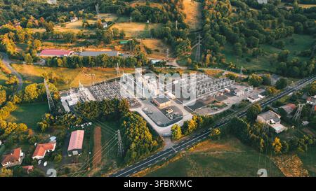 Luftbild eines Umspannwerks, umgeben von üppigen grünen Feldern, Bäumen und Stromleitungen während der goldenen Stunde in Orcines, Auvergne-Rhone-Alpes, F Stockfoto