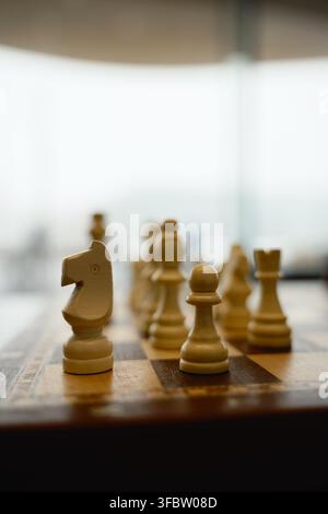 Helsinki, Finnland - 1. März 2026: Holzschachfiguren stehen auf einem Schachbrett in sanftem Innenlicht. Stockfoto