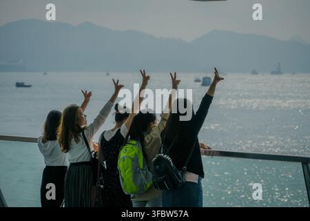 Eine Gruppe von fünf jungen Personen, von hinten gesehen, hebt die Hände in die Luft, wobei drei Friedenszeichen und zwei Shaka-Gesten machen, als die Stockfoto