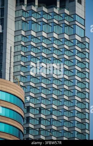 Das zeitgenössische Hochhaus verfügt über eine auffällige Fassade aus hellblau getönten Glasfenstern, die von hellgrauem Beton gerahmt sind, und schafft ein kunstvolles Stockfoto