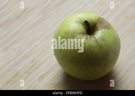 Nahaufnahme eines Granny-Smith-Apfels (Malus domestica) mit Wassertropfen vor einem Holz-Hintergrund. Konzept: lecker, Obst, frisch, Mittagessen, Hausapfel Stockfoto
