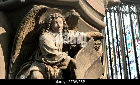 Historische Steingestaltskulptur, die von Sonnenlicht beleuchtet wird, neben Buntglasfenstern im Kölner Dom in Köln, Deutschland. Stockfoto