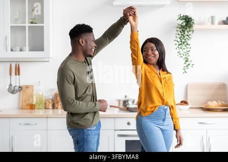 Glückliches junges afroamerikanisches Paar tanzt zusammen in der Küche, freudige Momente zu Hause Stockfoto