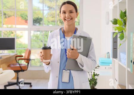 Gesundheitsfachkraft mit Kaffee und Klemmbrett, medizinische Karriere und Wohlbefinden, junge Ärztin in einem modernen Klinikbüro Stockfoto