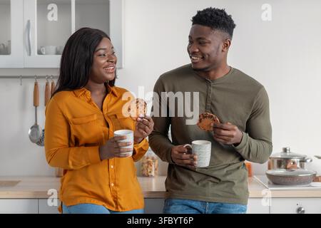 Glückliches schwarzes Paar genießt Kekse und Kaffee in einer modernen Küche, Lifestyle-Konzept Stockfoto