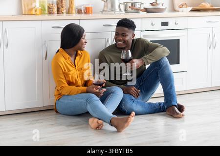 Glückliches schwarzes Paar genießt Wein während des Entspannens zu Hause in der Küche Stockfoto
