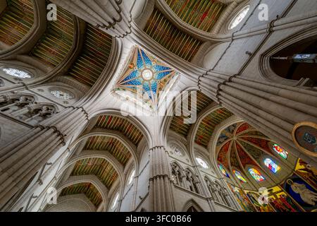 Ein atemberaubender Blick nach oben auf das kunstvoll verzierte Gewölbe und die Buntglasfenster in der Kathedrale von Madrid Stockfoto