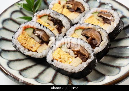 Nahaufnahme von japanischen Futomaki-Dick-Sushi-Rollen auf gemusterter Keramikplatte Stockfoto