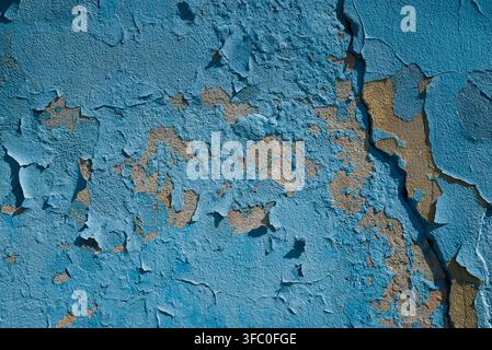 Nahaufnahme der Textur von abblätternder blauer Farbe, die von einer verwitterten Betonwand abfällt und darunterliegende rissige Putz- und Steinsschichten freilegt Stockfoto