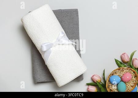 Oberansicht eines Stapels weißer und grauer Handtücher und eines Osterkorbs voller Eier Stockfoto