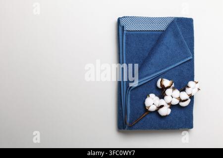 Oberansicht eines gefalteten blauen Handtuchs mit Baumwollzweig auf grauem Hintergrund Stockfoto