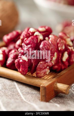 Nahaufnahme von roten Walnusskernen auf einem Holztablett mit unscharfem Hintergrund. Stockfoto