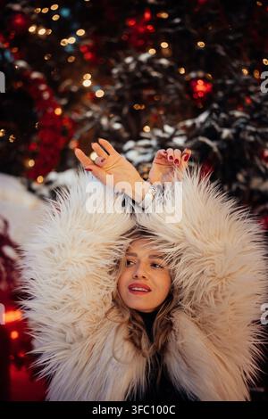 Frau genießt die Winterurlaubatmosphäre in einer gemütlichen Umgebung mit festlichen Dekorationen und Lichtern Stockfoto