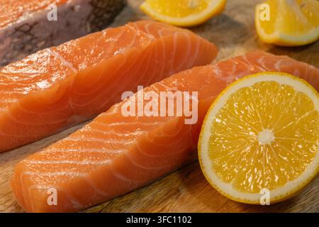 Frische rohe Lachsfilets, garniert mit Zitronenscheiben, sind auf einem Teller arrangiert. Stockfoto