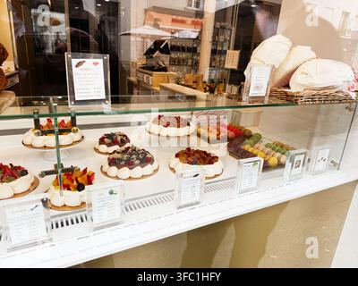 Paris, Frankreich – 14. Mai 2026: Gläserne Backtheke in Paris, Frankreich, gefüllt mit Pavlovatörtchen, Macarons, Biskuitkuchen und farbenfrohen Desserts. Stockfoto