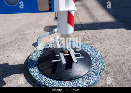 Hydraulisches Auslegbeinstütze einer großen Kräne mit einem stabilisierenden Stützpolster, das auf einer Betonoberfläche ruht. Schwerlast-Hebeausrüstung Stockfoto