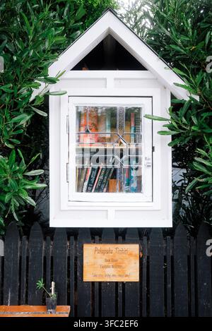 Christchurch, Neuseeland: Nahaufnahme eines hausförmigen Holzschilds der Pukapuka Tiritiri-Buchbibliothek auf einem schwarzen Zaun im Vorort St. Martins, Südinsel-Bibliothek Stockfoto
