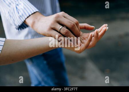 Nahaufnahme der Hand eines Mannes mit Ehering, der sanft die Hand einer Frau hält, symbolisch für Liebe, Ehe und Verbindung. Stockfoto