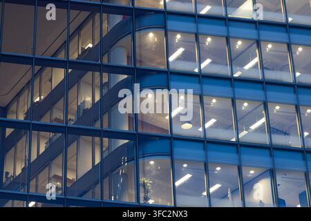 Beleuchtete Bürofenster an einer modernen Glasfassade Stockfoto