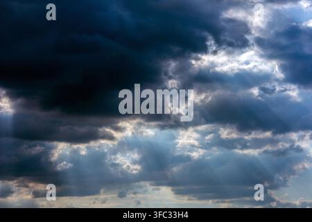 Dramatische dunkle Sturmwolken teilen sich, während Sonnenstrahlen in einem kraftvollen Himmelsbild in Spanien durch den Himmel brechen. Stockfoto