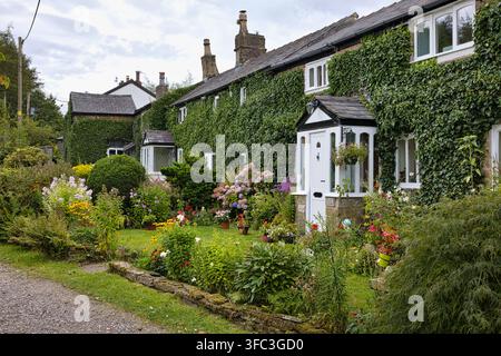 Malerische efeubedeckte Steinhäuschen mit bunten Vorgärten im Dorf Ainsworth in der Nähe von Bury, Greater Manchester, UK. Stockfoto