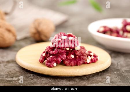 Rote Walnusskerne auf einem Holzteller mit unscharfen Walnüssen im Hintergrund. Stockfoto