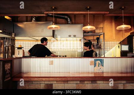 Zwei Männer arbeiten in einer geschäftigen offenen Küche eines Ramen-Restaurants in Gwangbok-dong, Busan, Südkorea. Stockfoto