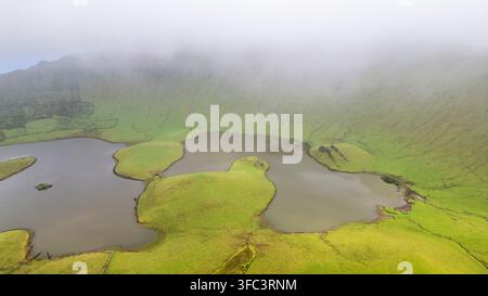 Corvo, Azoren, Portugal Luftaufnahme von nebelbedeckten Vulkansseen, die in üppigen grünen Hügeln eingebettet sind. Nebel bedeckt die Landschaft und erzeugt ein weiches, ätherisches Li Stockfoto