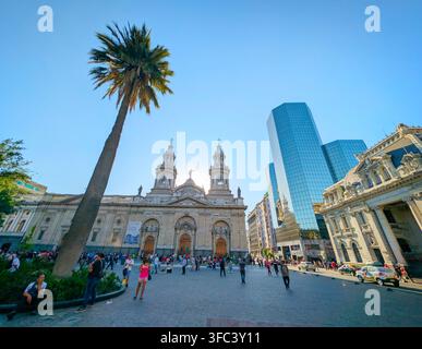 SANTIAGO, CHILE - 03. DEZEMBER 2025: Menschen gehen an der historischen Metropolitankathedrale von Santiago und dem modernen Glaskoloss an der Plaza de Armas vorbei Stockfoto