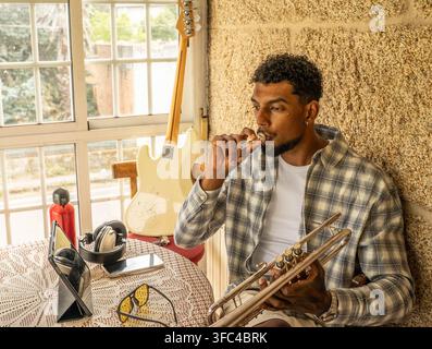 Junger Musiker ruht drinnen mit Trompete in der Hand Stockfoto