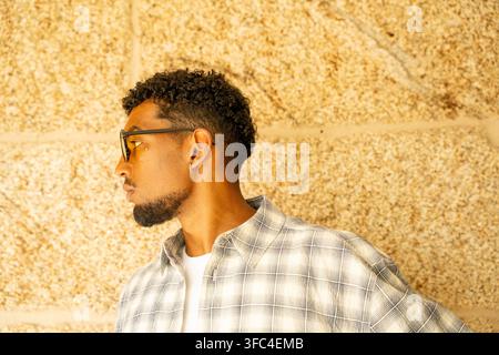Seitenansicht-Porträt eines jungen Mannes mit lockigem Haar, Brille, Ohrringen Stockfoto