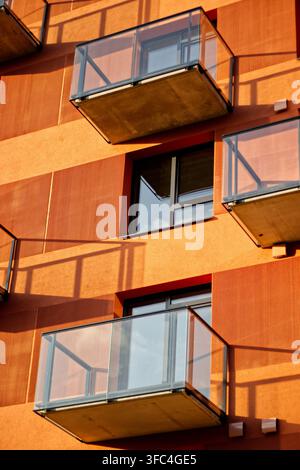 Moderne Glasbalkone an der Fassade eines orangefarbenen Wohnhauses Stockfoto