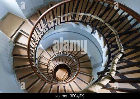 Spiraltreppe im Phare de la Garoupe-Leuchtturm in Antibes, Frankreich, von oben gesehen mit Holzgeländern, Seilgeländer und geometrischen Stufen. Stockfoto