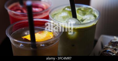 Nahaufnahme von verschiedenen kalten To-go-Getränken, darunter Eismatcha-Grüntee, Pfirsich-Eistee und Beeren Saft. Stockfoto