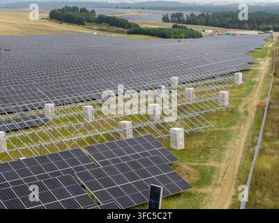 Luftaufnahme einer großen Photovoltaikanlage im Bau mit Reihen von Solarmodulen, die auf Metallrahmen in einer ländlichen Landschaft in Tokarnia, Swieto montiert sind Stockfoto