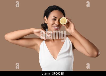Natürlichkeit und Hautpflegekonzept, glückliche junge afroamerikanische Frau mit Zitronenscheibe über dem Auge, gesunder Lebensstil Stockfoto