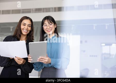 Porträt von zwei weiblichen Teamkolleginnen, die ein Tablet und Dokumente halten Stockfoto