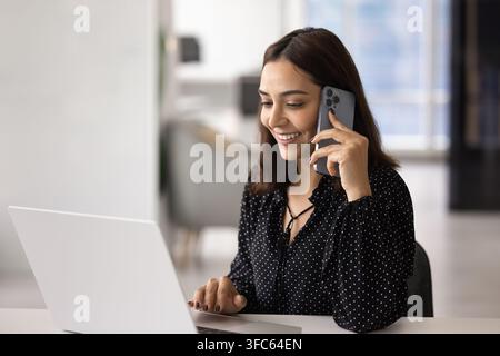 Lächelnde Geschäftsfrau telefoniert während der Arbeit Stockfoto