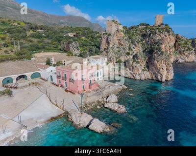 Luftaufnahme der Tonnara di Scopello, einer historischen Thunfischerei mit rosa Gebäuden und Steintürmen auf schroffen Klippen über dem türkisfarbenen Tyrrhenischen Meer Stockfoto