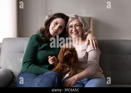 Porträt von Frauen verschiedener Generationen, die mit einem Hund auf einer Couch sitzen Stockfoto