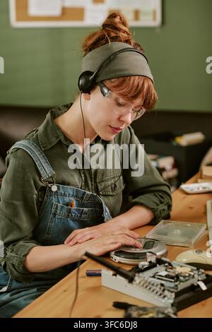 Frau hört einen tragbaren CD-Player in einem Retro-Büro Stockfoto