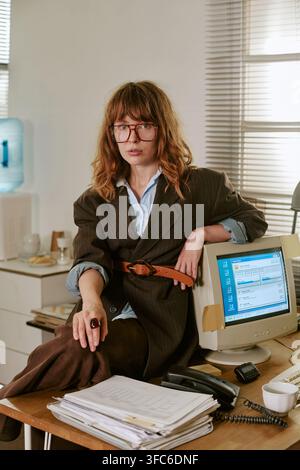 Porträt einer Frau, die an einem Schreibtisch in einem Retro-Büro sitzt Stockfoto