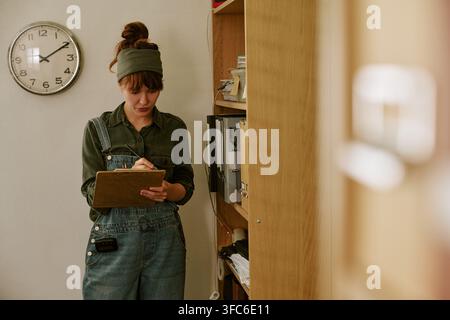 Frau schreibt auf Klemmbrett in Retro-Büro und arbeitet als Archivarin Stockfoto