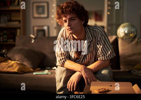 Porträt eines Mannes, der auf einem Sofa auf einer Hausparty sitzt Stockfoto