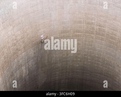 Luftaufnahme des Inneren eines großen Beton-Kühlturms mit einer kleinen Wartungsplattform, die an der gewölbten Wand im Vereinigten Königreich aufgehängt ist Stockfoto